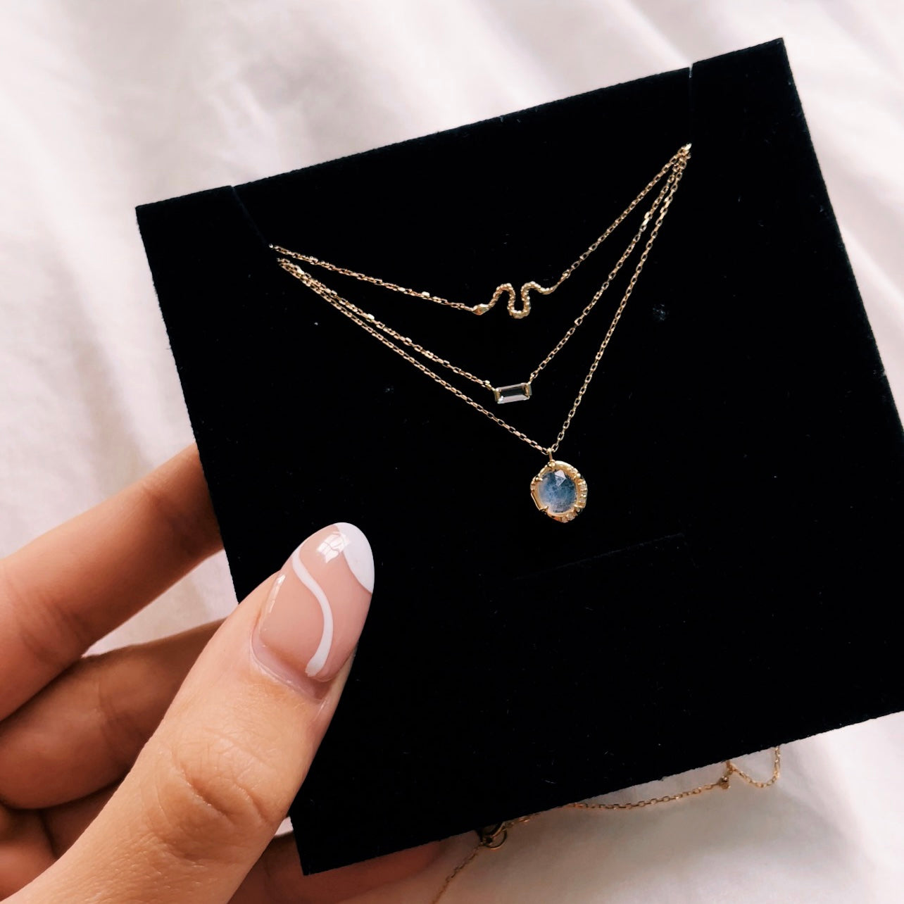 serpent necklace, white topaz necklace, and moonstone diamond necklace layered in packaging
