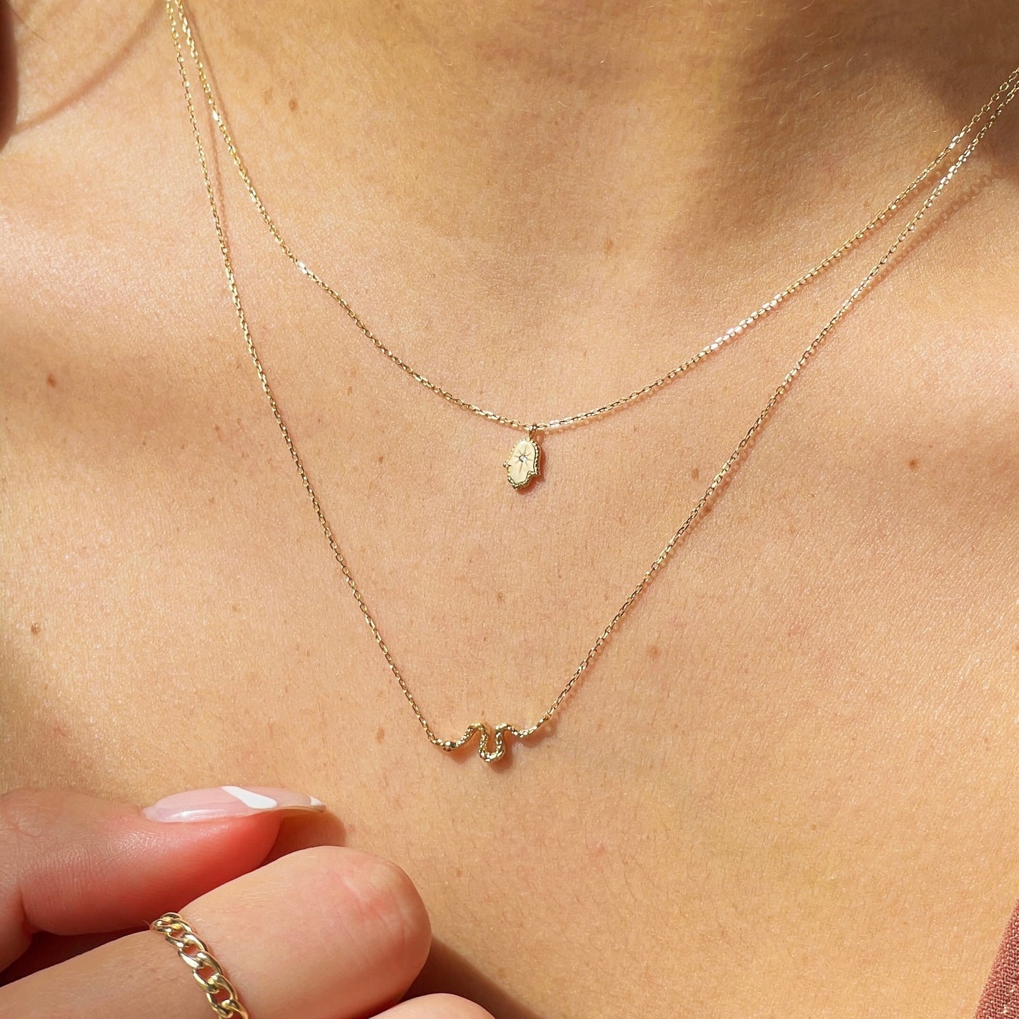 a fatima hamsa hand necklace and a snake necklace
