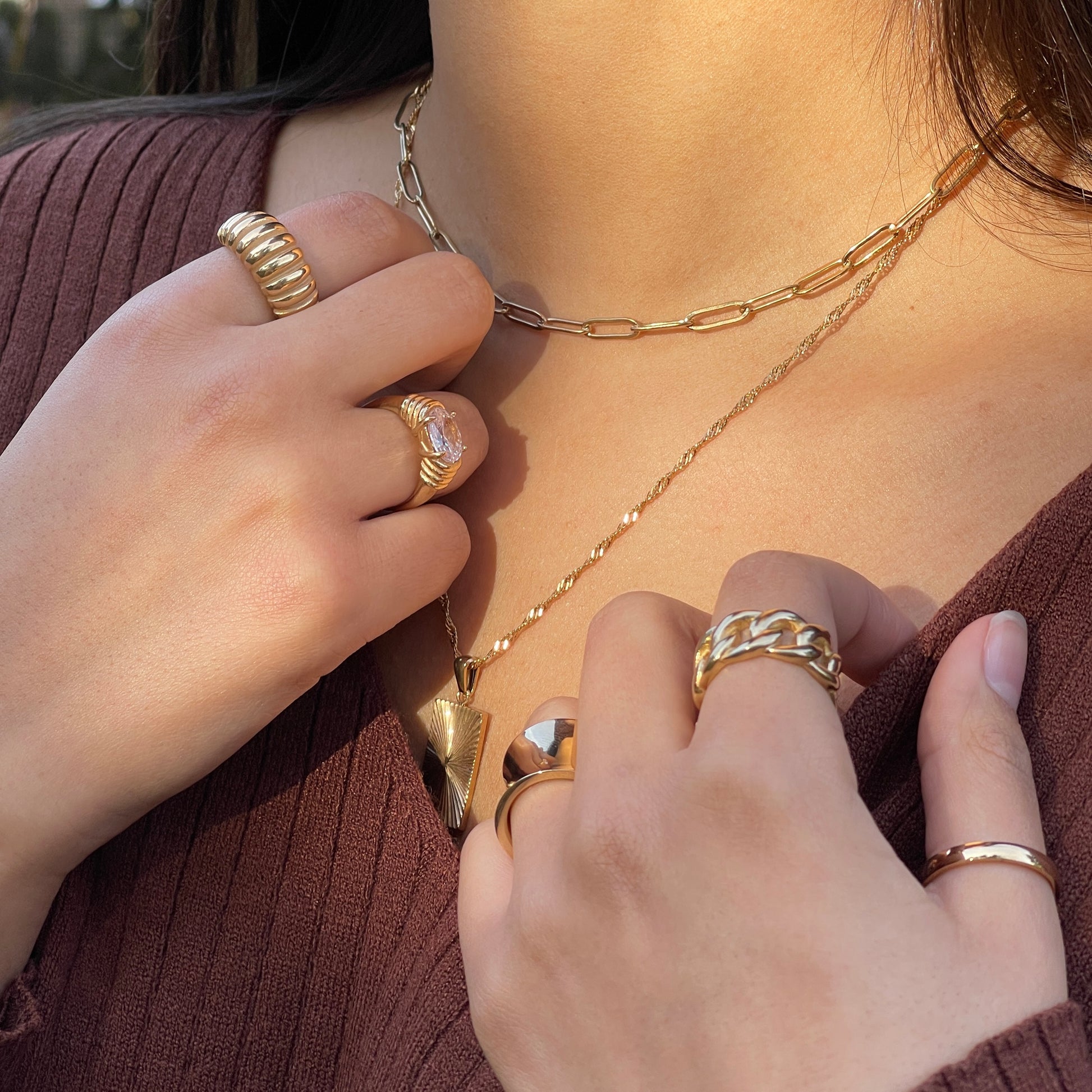 necklaces stacked, gold rings and gold jewelry layered on model