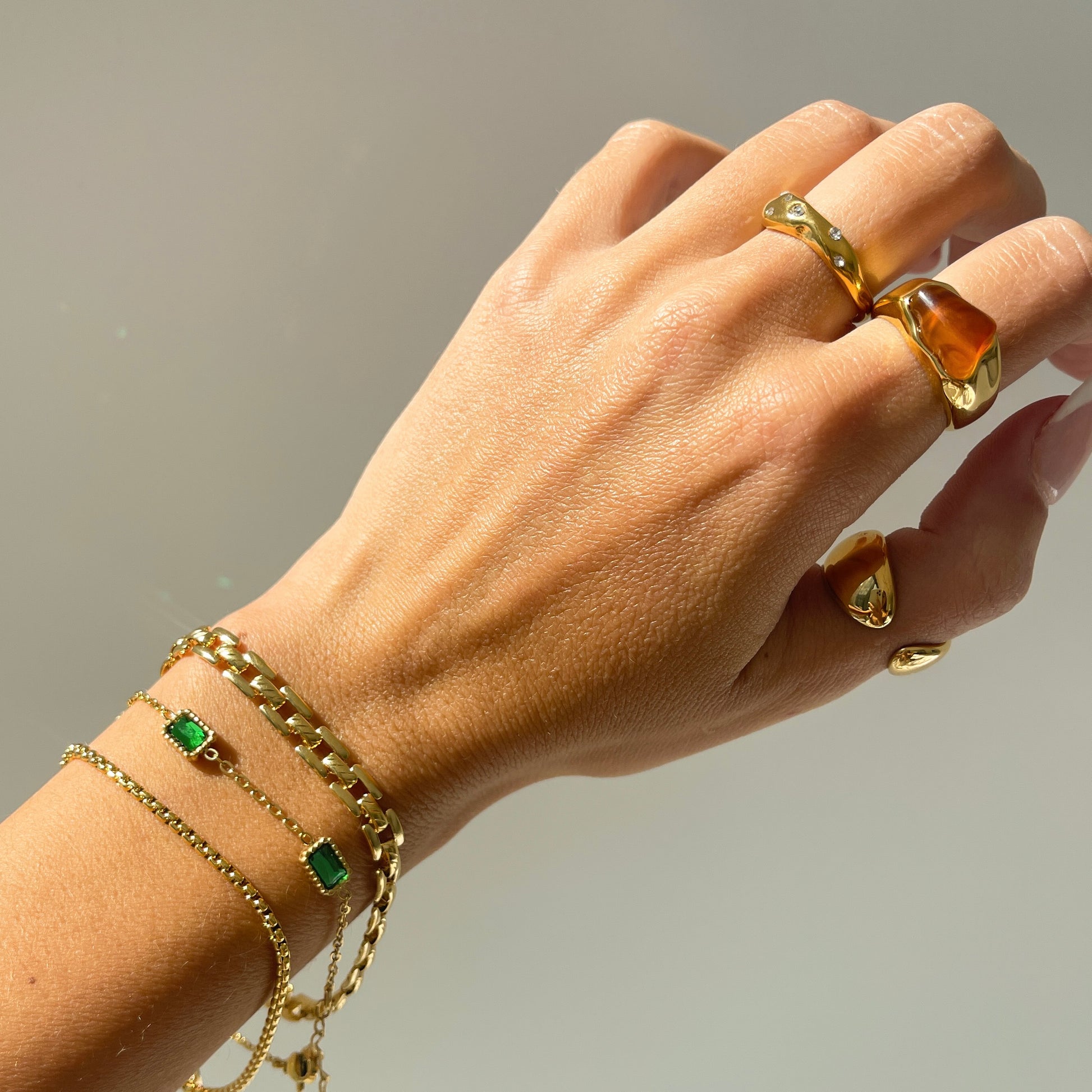 18k gold agate ring on hand with irregular stone ring and stacked gold bracelet chains
