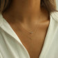 14k gold XO necklace layered with a triple moonstone pendant on tan skin collarbones